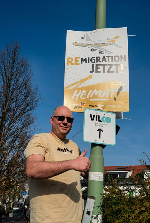 Spitzenkandidat Daniel Lachmann von HEIMAT Wetterau beim Plakatieren auf einer Leiter an einer Straßenlaterne