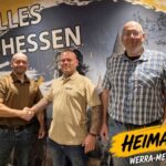 Drei Vertreter der Partei Die Heimat Werra-Meißner-Kreis stehen vor einer Wandaufschrift mit der Losung „Alles für Hessen“.